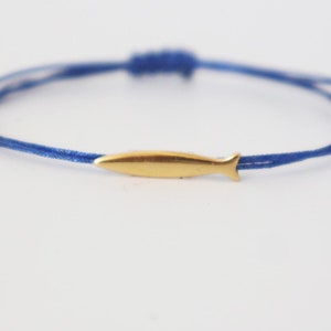 May include: A blue cord bracelet with a gold fish charm.