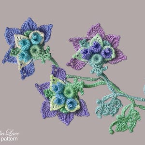 May include: A crocheted flower pattern with three flowers in shades of blue, green, and purple. The flowers are connected by a stem with leaves. The text "Taniwha Lace flower pattern" is at the bottom of the image.