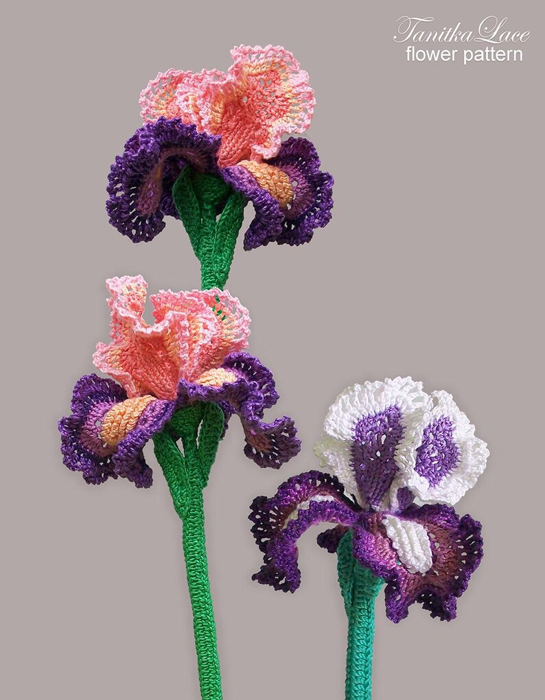 May include: Crocheted iris flowers in shades of pink, purple, and white with green stems. The flowers have detailed petal work and are arranged against a neutral background. The text "Tanitka Lace flower pattern" is in the upper right corner.