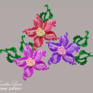 May include: Three crocheted flower appliqu&eacute;s with green leaves. One flower is pink with a pale yellow center, one is purple with a light pink center, and one is violet with a light pink center. The text Tanitka Lace flower pattern is visible.