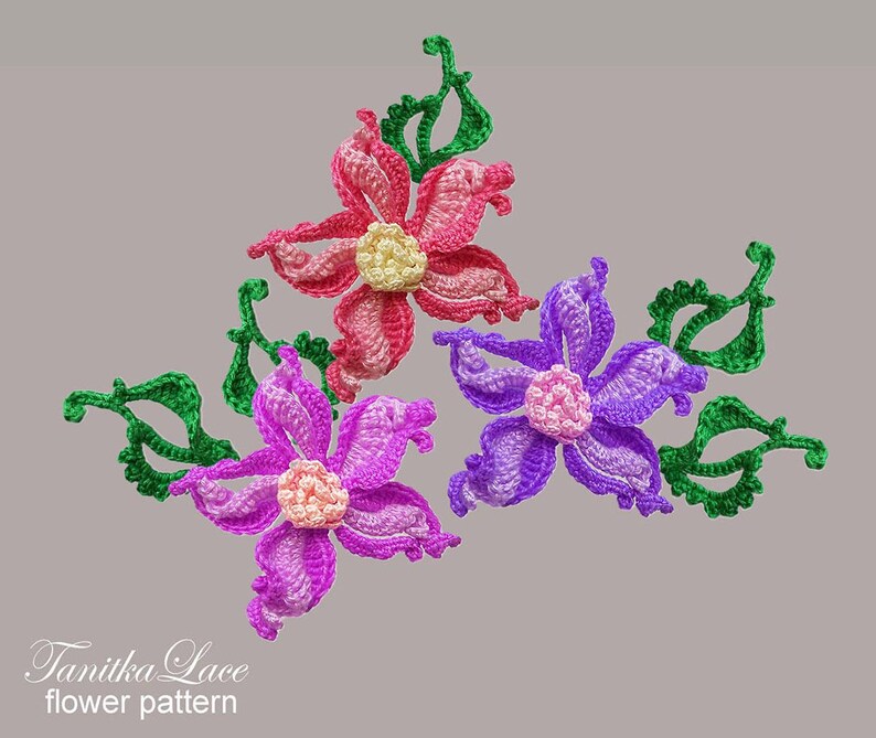 May include: Three crocheted flower appliqu&eacute;s with green leaves. One flower is pink with a pale yellow center, one is purple with a light pink center, and one is violet with a light pink center. The text Tanitka Lace flower pattern is visible.