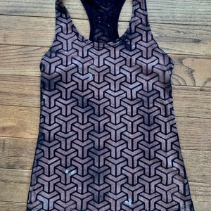 May include: A black tank top with a geometric pattern in shades of brown. The pattern is a repeating design of interlocking triangles.