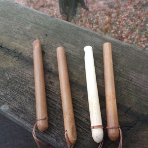 May include: Four wooden dowels with leather straps. Three are brown and one is white.