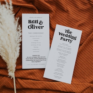 May include: A wedding ceremony program with the names Britt & Oliver printed in bold black text. The program lists the order of events for the ceremony and the wedding party. The program is printed on white cardstock and is lying on a brown textured surface.