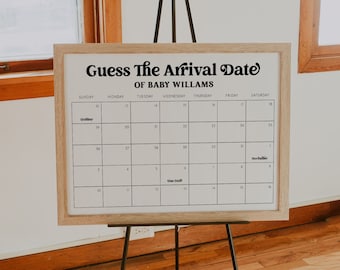 May include: A white sign with a wooden frame on an easel. The sign says "Guess The Arrival Date of Baby Williams" and has a calendar with the month of October.