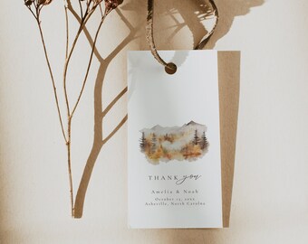 May include: A white thank you tag with a watercolor illustration of a mountain landscape in autumn colors. The text reads "THANK you Amelia & Noah October 13, 20xx Asheville, North Carolina".