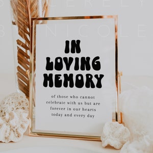 May include: A gold-framed sign with the text "In Loving Memory" in a retro font. The sign also includes the text "of those who cannot celebrate with us but are forever in our hearts today and every day."