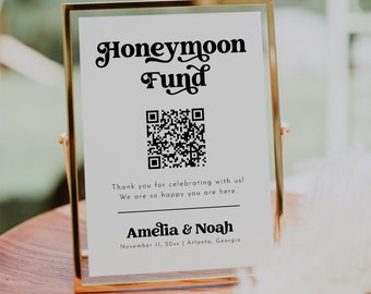 Könnte beinhalten: Ein weißes Schild mit goldenem Rahmen, auf dem in dekorativer Schrift "Honeymoon Fund" steht. Unter dem Text ist ein QR-Code abgebildet, gefolgt von der Nachricht "Vielen Dank, dass Sie mit uns feiern! Wir freuen uns sehr, dass Sie da sind." Das Schild ist mit "Amelia & Noah" signiert und enthält das Datum "11. November 20xx" und den Ort "Atlanta, Georgia".