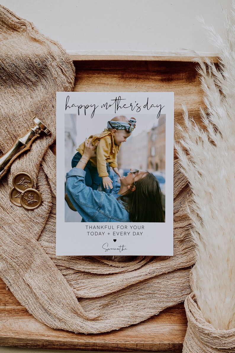 K&ouml;nnte beinhalten: Eine wei&szlig;e Karte mit dem Text "happy mother's day" in schwarzer Schrift. Ein Foto einer Frau, die ein Kind h&auml;lt, befindet sich in der Mitte der Karte. Der Text "thankful for your today + every day" befindet sich unter dem Foto. Ein Herzsymbol und der Name "Samantha" befinden sich unter dem Text.
