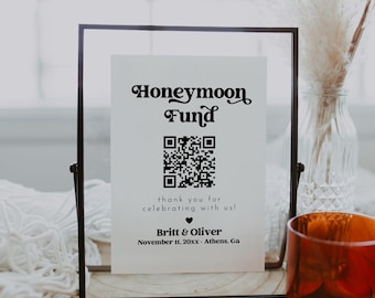 Könnte beinhalten: Ein schwarzes gerahmtes Schild mit weißem Hintergrund und dem Text "Honeymoon Fund" in einer Retro-Schrift. Unter dem Text befindet sich ein schwarz-weißer QR-Code, gefolgt vom Text "thank you for celebrating with us!" und den Namen "Britt & Oliver" mit dem Datum "November 11, 20xx - Athens, Ga".
