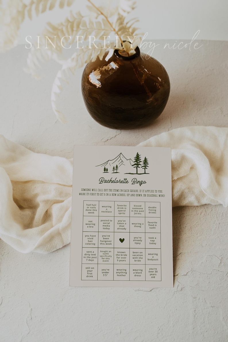 A rustic bachelorette bingo game card featuring a minimalist mountain design. The card includes a grid of playful prompts for a fun and interactive pre-wedding celebration. Perfect for outdoor-themed or adventure-loving brides.