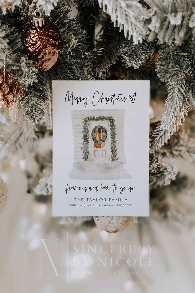 May include: A white Christmas card with a watercolor illustration of a house with a wreath on the door. The text on the card reads "Merry Christmas" and "from our new home to yours." The card also includes the text "THE TAYLOR FAMILY" and "1600 Evergreen Trace | Atlanta, GA 00000".