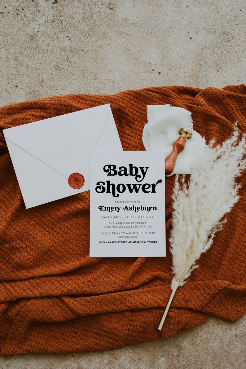Op de afbeelding: Een witte babyshower-uitnodiging met zwarte tekst. De uitnodiging luidt "Baby Shower" in een retro-lettertype, gevolgd door "honoring mom-to-be Emery Asheburn". De datum, locatie en RSVP-informatie staan hieronder vermeld.