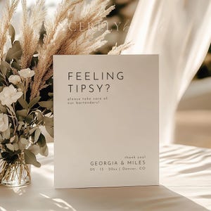 May include: White sign with black text that reads "Feeling Tipsy? Please take care of our bartenders!" and "Thank you! Georgia & Miles 05-13 20xx | Denver, CO".