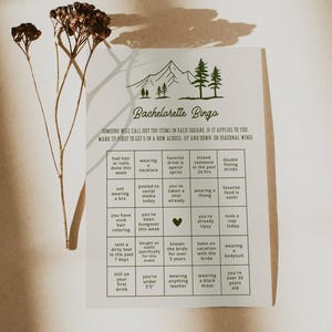 A bachelorette bingo game card styled in warm sunlight with dried floral accents. This interactive game encourages guests to mark off fun and memorable experiences, ideal for bridal parties with a natural or boho theme.