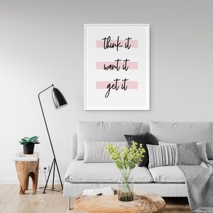 May include: A white framed print with the text "think it, want it, get it" in black script. The text is underlined with a pink stripe.