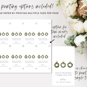 May include: White printable Christmas gift tags with green wreath illustrations and the text "merry christmas + happy new year". The design includes multiple printing options and trim marks.