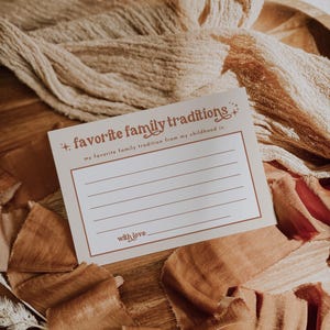 A nostalgic fill-in card placed on textured fabric with warm brown hues. Designed for capturing cherished childhood traditions, making it a beautiful addition to baby showers or seasonal celebrations.