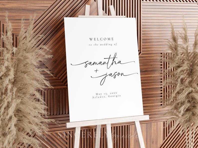 Modern wedding welcome sign on a white easel, styled with pampas grass and a geometric wood backdrop. A stylish addition to a contemporary wedding setting.
