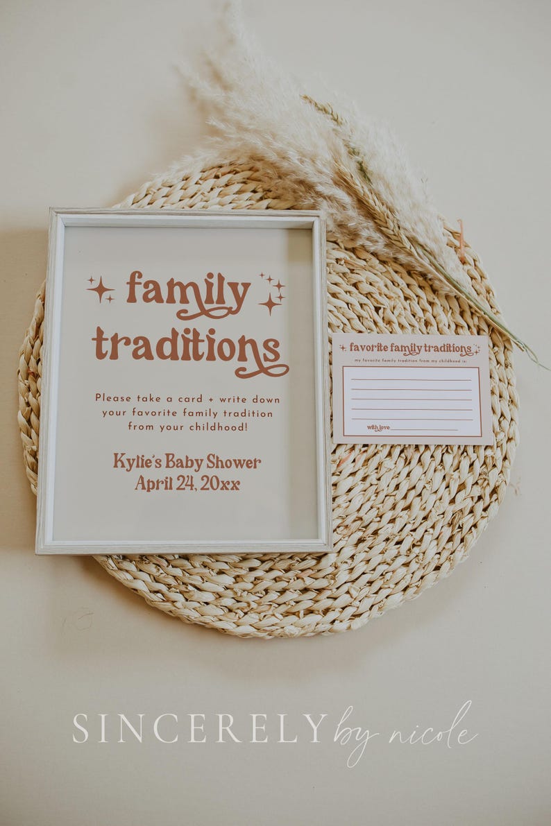 A framed baby shower sign and matching card encourage guests to write down special family traditions. With soft neutral tones and rustic pampas grass, this sentimental setup adds a personal element to the event.