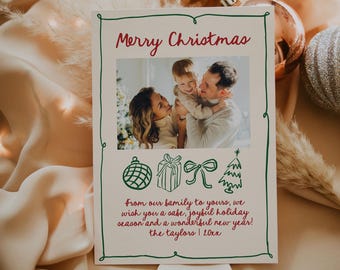 May include: A Christmas card with a green border and a photo of a family of three. The card reads "Merry Christmas" in red lettering and "From our family to yours, we wish you a safe, joyful holiday season and a wonderful new year! The Taylors | 20xx".