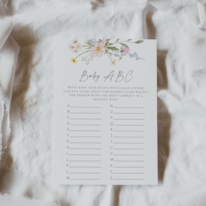 May include: A printable baby shower game card with a floral design. The card has the title "Baby ABC" and instructions for a game where guests guess what baby items start with each letter of the alphabet.
