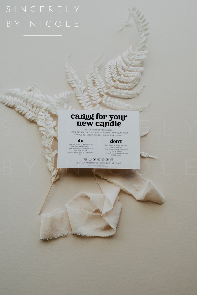 May include: A white card with black text that reads "caring for your new candle" with instructions on how to care for a candle. The card is on a light beige background with white dried ferns and a white ribbon.