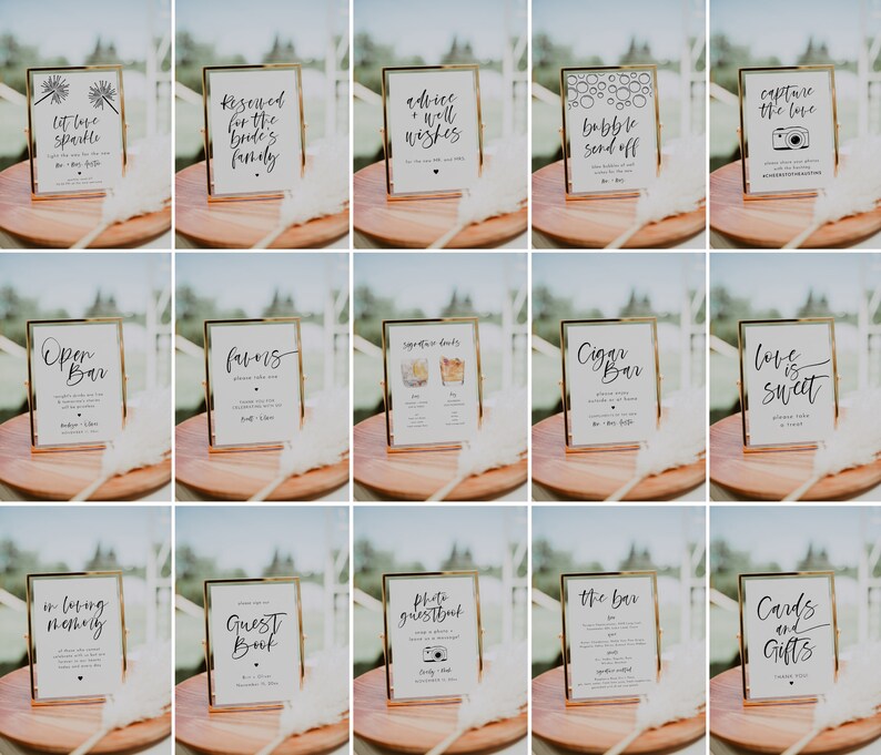 May include: A collection of framed wedding signs with gold frames and white backgrounds. Each sign features elegant black calligraphy with phrases like "Open Bar," "Capture the Love," and "Cards and Gifts." The signs are arranged on a wooden surface.