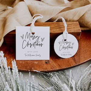 May include: Two white gift tags with black calligraphy that reads "Merry Christmas" with a heart on each side. The smaller tag is round and the larger tag is square. Both tags have the text "With Love, The Williamson Family" printed below the greeting.