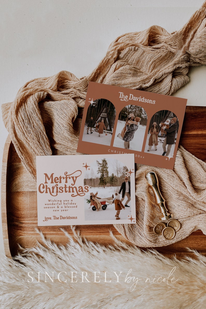 May include: A Christmas card with a retro font design that says "Merry Christmas". The card features a photo of a family in a snowy winter scene. The text "Wishing you a wonderful holiday season & a blessed new year" is written below the photo. The card is signed "Love, The Davidsons".