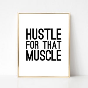 May include: Black and white motivational quote print in a gold frame. The quote reads "Hustle for that muscle."