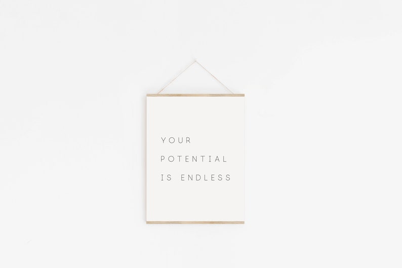 Puede incluir: Una impresi&oacute;n enmarcada blanca con el texto "YOUR POTENTIAL IS ENDLESS" colgada en una pared blanca.
