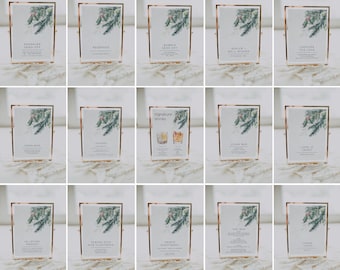 May include: A set of 12 gold-framed signs with a wintery pine branch design. Each sign has a different message, such as "Open Bar", "Signature Drinks", "Advice & Well Wishes", and "Cards & Gifts".