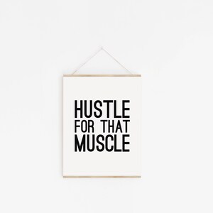 May include: A white framed motivational poster with black text that reads "Hustle for that Muscle".