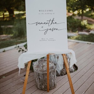Minimalist wedding welcome sign displayed on a wooden easel with soft fabric, set against a natural outdoor backdrop. A perfect choice for rustic and outdoor celebrations.