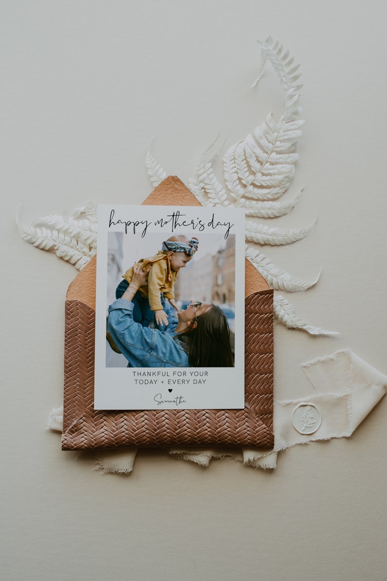 K&ouml;nnte beinhalten: Eine wei&szlig;e Karte mit dem Text "happy mother's day" in schwarzer Schrift. Die Karte zeigt ein Foto einer Frau, die ein Kind in die Luft h&auml;lt. Unter dem Foto steht der Text "thankful for your today + every day", gefolgt vom Namen "Samantha".