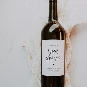 Może przedstawiać: Ciemnobrązowa butelka wina z białą etykietą. Etykieta głosi "AMELIA'S bridal shower" w skrypcie, ze znakiem serca i datą 11 listopada 20xx oraz lokalizacją Atlanta, Georgia.