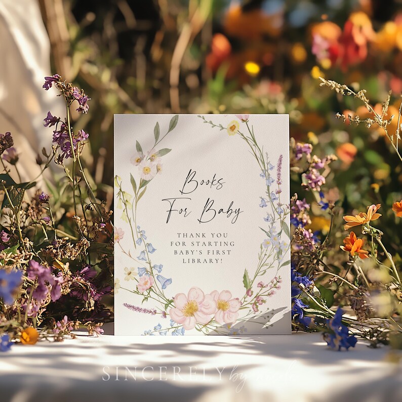 Books for baby sign with handwritten-style font and watercolor botanical details, set against a colorful wildflower backdrop, making it a beautiful addition to a garden-inspired baby shower setup.