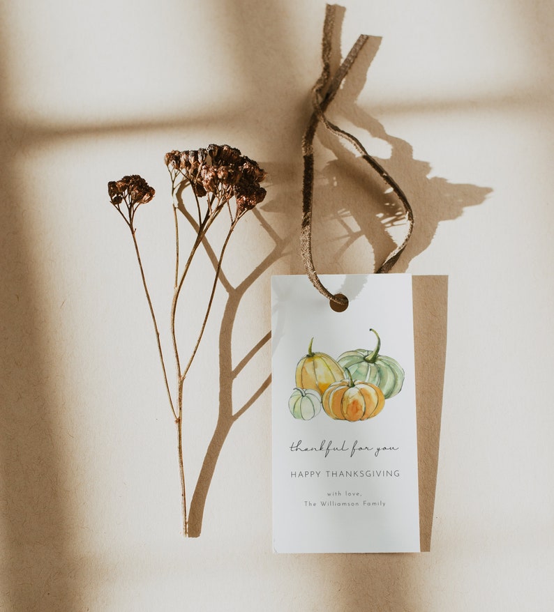 May include: A white gift tag with a watercolor illustration of three pumpkins. The tag has the text "thankful for you" and "HAPPY THANKSGIVING" with the words "with love, The Williamson Family" at the bottom.