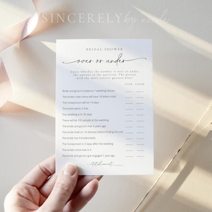 May include: A printable bridal shower game card with the title "Over or Under". Guests are asked to guess whether the number is over or under for various questions about the bride and groom. The game card is white with black text.