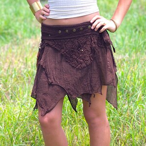 May include: A brown, asymmetrical skirt with a crocheted overlay and a brown leather belt with metal accents.