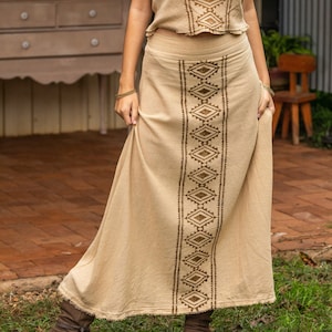 May include: A beige sleeveless top with a brown geometric pattern and a matching beige maxi skirt with a brown geometric pattern. The skirt has a raw hem.