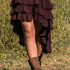 May include: A burgundy layered skirt with a high-low hemline. The skirt is made of a soft, flowing fabric and has a casual, bohemian style.