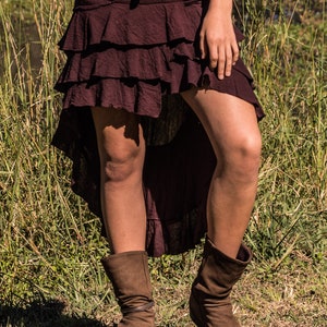 May include: A burgundy tiered skirt with a high-low hemline. The skirt is made of a soft, flowing fabric and has a casual, bohemian style.