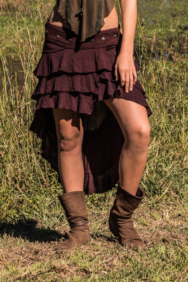 May include: A burgundy tiered skirt with a high-low hemline. The skirt is made of a soft, flowing fabric and has a casual, bohemian style.