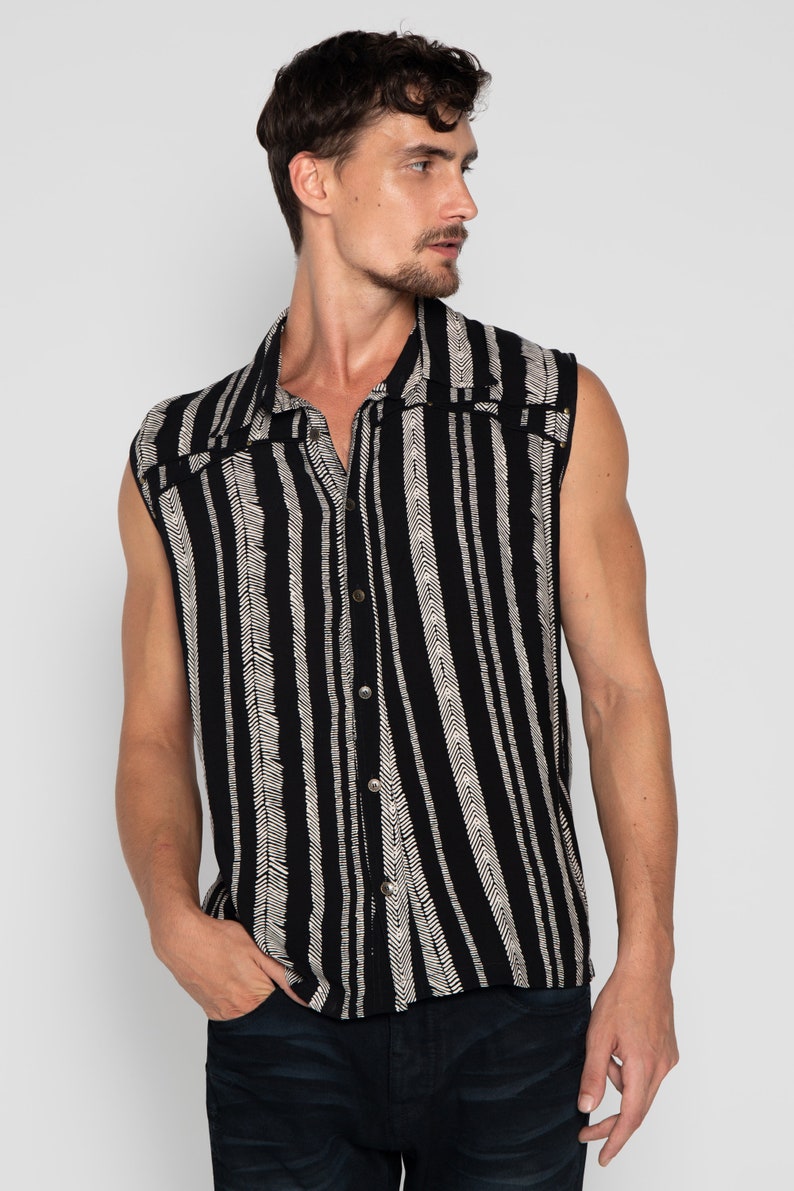May include: A sleeveless button-up shirt with a black and white striped pattern. The shirt has a collar and a button-up front.