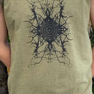 May include: A green sleeveless shirt with a black graphic print of a geometric design with a circle in the center.