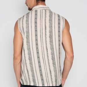 May include: A sleeveless shirt with a white background and black vertical stripes. The stripes are made up of small, repeating patterns.