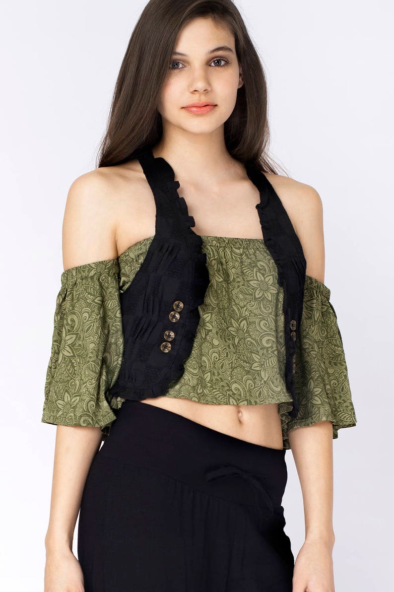 May include: A black sleeveless vest with a ruffled neckline and four gold buttons. The vest is worn over a green floral print top.