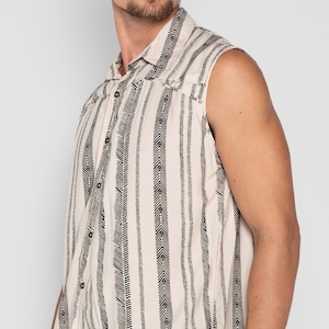 May include: A sleeveless button-up shirt with a white background and black chevron pattern. The shirt has a collared neckline and a button closure.